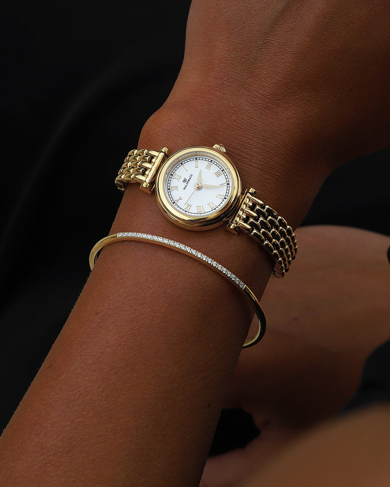 A round womens watch in 22k gold plated 316L stainless steel from Waldor & Co. with white Sapphire Crystal glass dial. Seiko movement. The model is Venia 24 Villefranche.