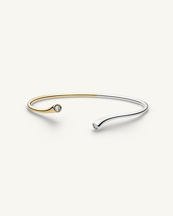 A polished stainless steel bangle in 14k gold from Waldor & Co. One size. The model is Delight Bangle.