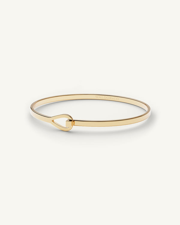 A Bangle Bracelet in 14k gold-plated from Waldor & Co. The model is Signature Bangle Polished Gol