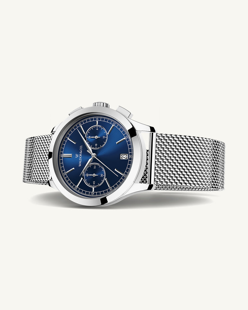 En rund herrklocka i rodiumpläterat silver från WALDOR & CO. med blå sunray urtavla och en sekundvisare. Seiko urverk. Modellen är Chrono 44 Sardinia 44mm. 