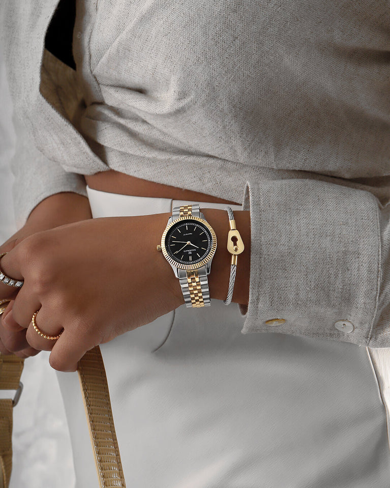  A round womens watch in silver and 22k gold from Waldor & Co. with black sunray dial and a second hand. Seiko movement. The model is Imperial 32 Positano 32mm.